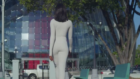 A-young-girl-wearing-a-white-bodysuit-delights-in-a-day-in-the-city-with-a-performing-arts-center-in-the-background