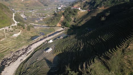 Aerial-drone-shot-of-valley-filled-with-bright-green-rice-terraces-in-the-mountains-of-Sapa,-Vietnam