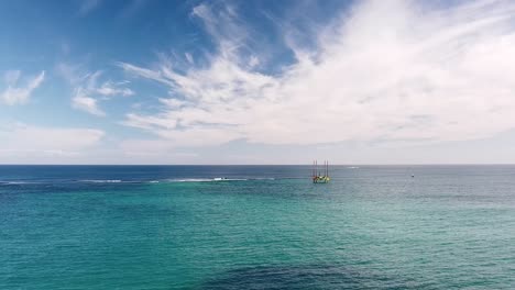 Vista-Aérea-Sobre-Aguas-Poco-Profundas-Del-Arrecife-Alkimos-Cerca-De-Eden-Beach-Perth-Con-Plataforma-De-Perforación-En-Segundo-Plano.