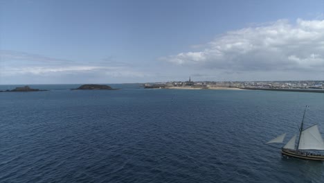 Drone-footage-of-the-corsair-boat-Le-Renard-in-the-sea-and-Saint-Malo-in-background,-Bretagne,-France