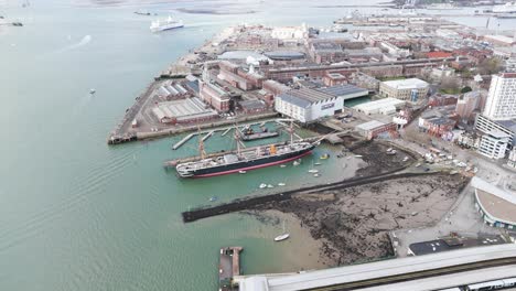 Dropping-drone-footage-of-HMS-Warrior-in-Portsmouth-Docks-with-Naval-Base-beyond-and-busy-harbour-with-ferries