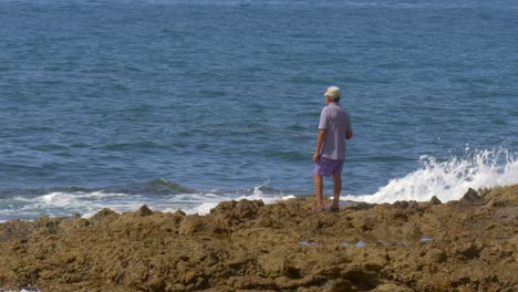 Old-man-fishing-in-the-ocean-in-the-afternoon