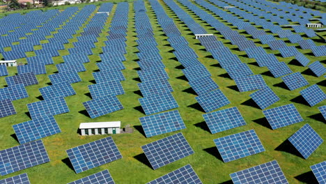 Rows-of-solar-panels-on-a-green-field-during-daytime,-aerial-view