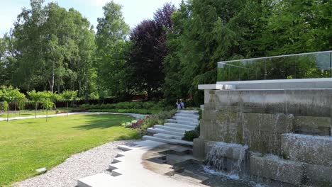 Parque-Verde-Con-Cascada-Durante-Un-Hermoso-Día-De-Verano-Rodeado-De-Exuberante-Vegetación-Y-Césped