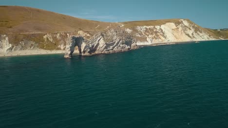 Aerial-shot-orbiting-around-Durdle-door,-a-natural-limestone-arch-on-the-Jurassic-Coast-near-Lulworth,-England