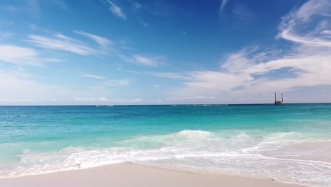 Waves-lapping-shore-with-geological-drilling-platform-at-Eden-Beach,-Perth