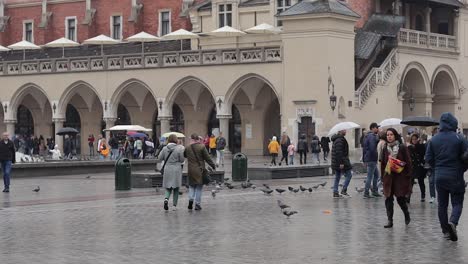 Plaza-En-Cracovia-Con-Gente-Pasando-En-Tiempo-Lluvioso-Con-Sombrillas.