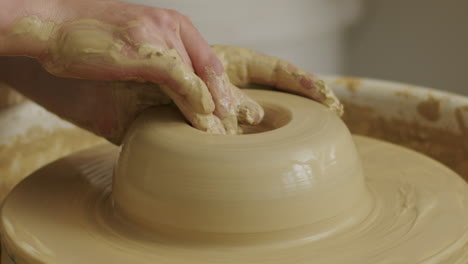 Handheld-close-up-shot-of-pushing-the-clay-inwards-with-the-hands-to-form-a-hole-for-a-vase