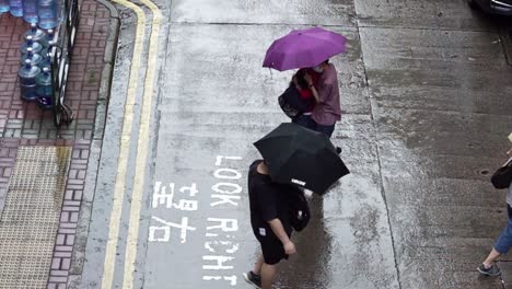 Menschen-überqueren-Die-Straße-Unter-Regenschirmen-Im-Regen,-Mong-Kok,-Hongkong,-Zeitlupe