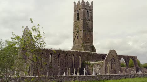 Claregalway-Friary-side-angle-view-of-tombstone-and-cemetery-below-decrepit-ruins