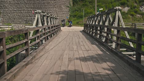 Rustic-wooden-bridge-leading-to-lush-greenery-and-motorcycles-parked-at-the-end-in-Rastoke,-Croatia