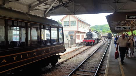 Crowds-of-people-on-platform-at-Dartmouth-Steam-Railway-with-steam-train-on-tracks-at-Kingswear-station-traveling-across-to-popular-tourism-destination-of-Dartmouth-in-Devon,-England-UK