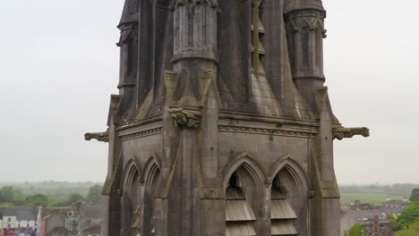 Saint-Michael's-Church-in-Ballinasloe-Galway,-aerial-pan-and-orbit-around-mid-section-with-stone-statues