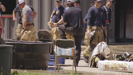 Firefighters-gather-outside-a-metal-building-during-a-sunny-day-in-Siloam-Springs,-Arkansas