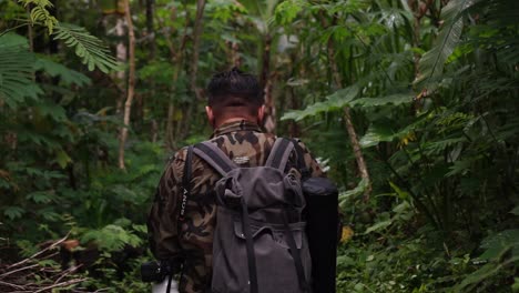 Back-view-of-Asian-wildlife-photographer-man-walks-through-tropical-rainforest