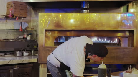 Un-Hombre-Preparando-Y-Deslizando-Una-Pizza-En-Un-Horno-De-Pizza