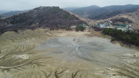 Aerial-perspective-of-the-volcanic-landscape-of-the-mountains-of-Romania-with-its-mud-volcanoes,-dry-land-with-cracks,-with-some-isolated-houses-and-villages