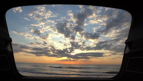 Slider-shot-of-the-sunset-and-sea-view-from-a-car's-trunk