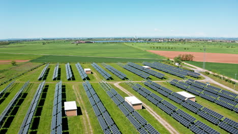 A-solar-farm-in-a-vast-green-field-on-a-sunny-day,-aerial-view