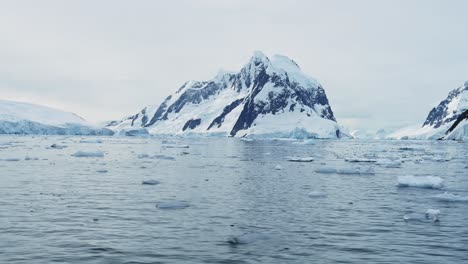 Aerial-drone-shot-of-Antarctica-Mountains,-Ocean-and-Scenery-at-Sunset,-Dramatic-and-Rugged-Antarctic-Peninsula-Coast-with-Southern-Sea-Water-on-Coastline,-Seascape-and-Landscape-with-Winter-Sea-Ice