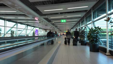 Pasajeros-En-Escaleras-Mecánicas-Móviles-Planas-Dentro-Del-Aeropuerto-Schiphol-De-Ámsterdam,-Países-Bajos