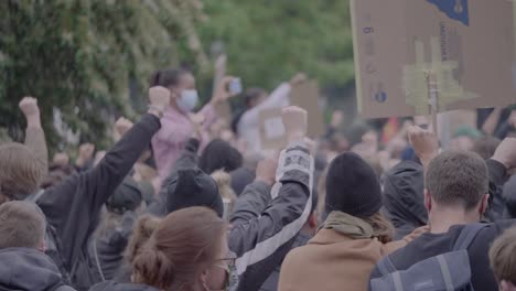 Eine-Menge-Demonstranten-Protestierten-Und-Hielten-Schilder-Gegen-Rassismus-Hoch,-Während-Sie-Bei-Einem-Black-Lives-Matter-Protest-In-Stuttgart,-Deutschland,-Klatschten-Und-Die-Fäuste-Erhoben.