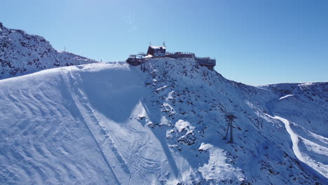 Aerial-shot-climbing-up-above-a-popular-ski-resort-to-the-highest-hotel-in-Europe,-perfect-blue-skies-surrounded-by-the-most-spectacular-scenic-mountain-landscape,-Glacier-Hotel-Grawand,-Tyrol,-Italy