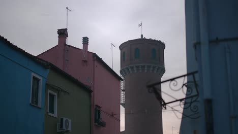 Coloridos-Edificios-Con-Una-Torre-Histórica-Al-Fondo-En-La-Isla-De-Burano,-Venecia,-Italia