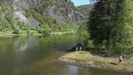 Women-and-two-young-girls-play-and-have-fun-on-a-small-island-in-middle-of-Norway-fjord