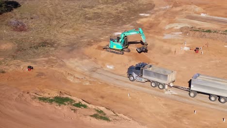 Yarrawonga,-Victoria,-Australien-–-29.-Mai-2024:-LKW-Und-Anhänger-Bringen-Sich-In-Position,-Damit-Ein-Raupenbagger-Erde-Von-Einem-Erdhaufen-Laden-Kann