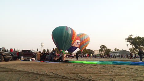 3-Globos-Aerostáticos-En-Tierra-Se-Preparan-Para-El-Despegue-Mientras-Una-Tripulación-Empaca-Un-Globo-Desinflado