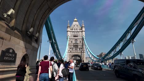 Dynamic-view-of-people-and-car-traffic-crossing-Tower-Bridge,-an-iconic-London-landmark,-bustling-with-activity