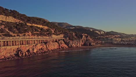 Scenic-sunrise-at-Port-Ginesta-in-Barcelona,-Spain-with-coastal-cliffs-and-calm-waters