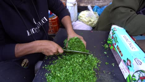 An-old-Arab-woman-cuts-parsley-at-Wadi-Nisnas-market,-filmed-in-slow-motion,-Haifa,-Israel