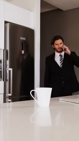 Businessman-talking-on-mobile-phone-in-kitchen