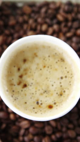 Disposable-cup-with-coffee-beans-on-wooden-plank