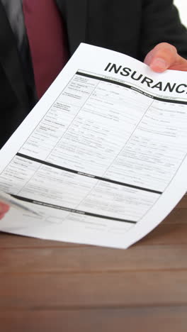 Businessman-sitting-at-desk-holding-insurance-contract