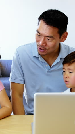 Familia-Feliz-Usando-Tableta-Digital-Y-Computadora-Portátil-En-La-Sala-De-Estar