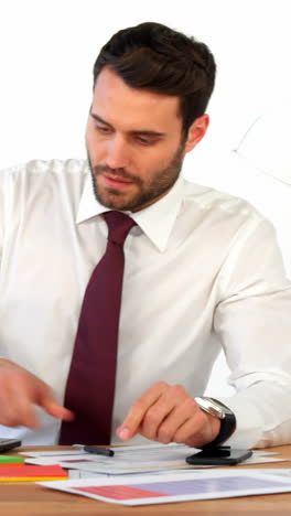 Businessman-working-at-his-desk-and-talking-on-mobile-phone