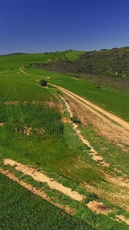 Aerial-view-of-a-dirt-road-winding-through-mountainous-terrain