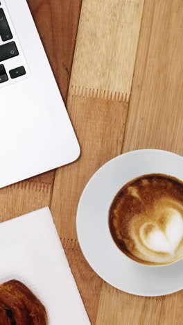 Close-up-of-laptop-with-coffee-cup-and-sweet-cookie