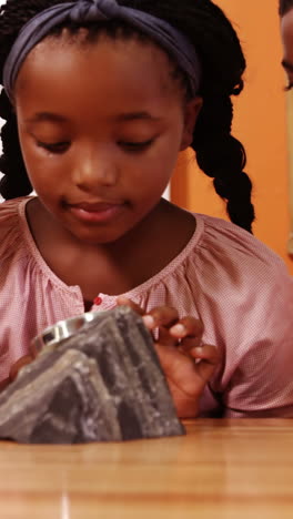 School-kids-using-magnifying-glass-over-rock