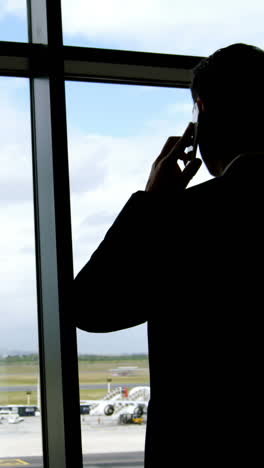 Businessman-talking-on-mobile-phone-at-airport