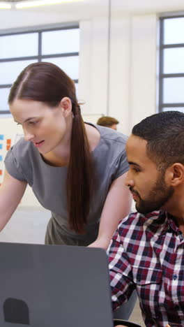 Business-executives-interacting-while-using-laptop