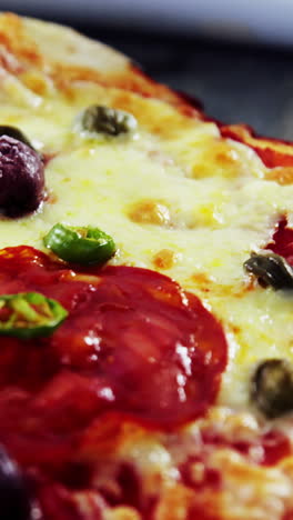 Baked-pizza-with-olive-and-peperoni-toppings-served-on-chopping-board