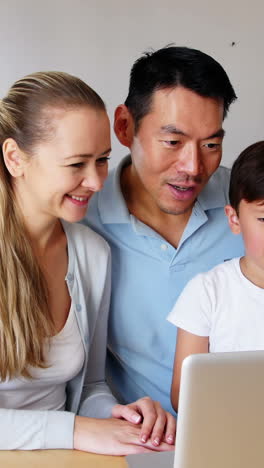 Familia-Feliz-Usando-Una-Computadora-Portátil-En-La-Sala-De-Estar