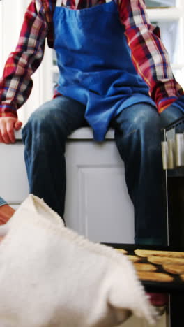 Father-and-son-removing-cupcakes-tray-from-oven