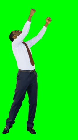 Excited-businessman-standing-against-green-background