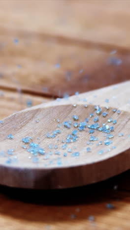 Crystals-of-blue-frit-glass-falling-wooden-spoon