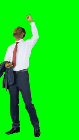 Excited-businessman-standing-against-green-background